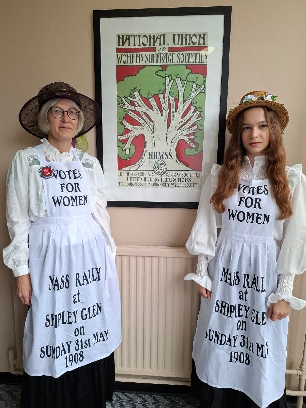 Two participants in Votes for Women aprons at the Suffrage Sisters launch